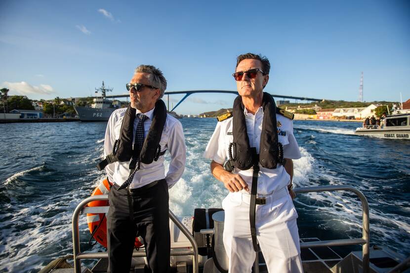 Premier Schoof en commandeur Hansen op een varende boot.