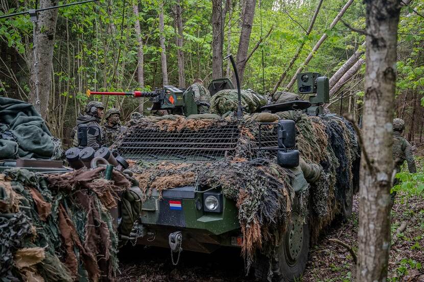 Militairen brengen in bosachtig gebied een gewonde collega naar het medisch behandelpunt.